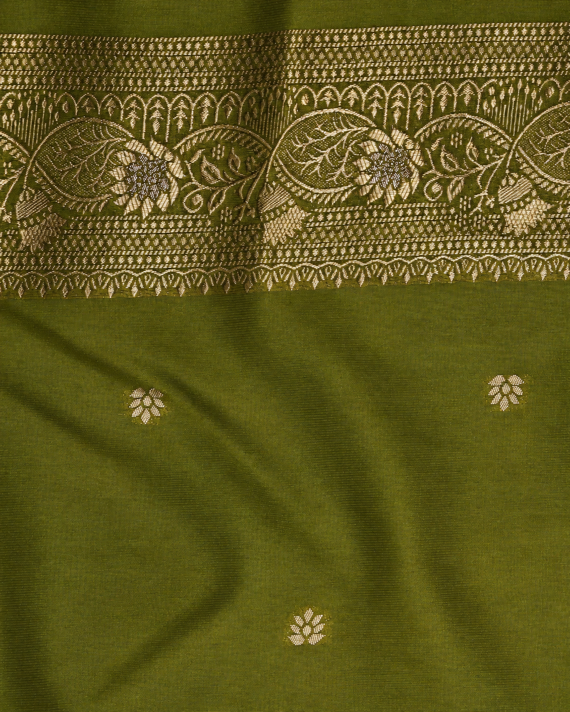 an olive green fabric close-up with a wide beige floral and geometric woven border across the top and small scattered beige floral motifs below.