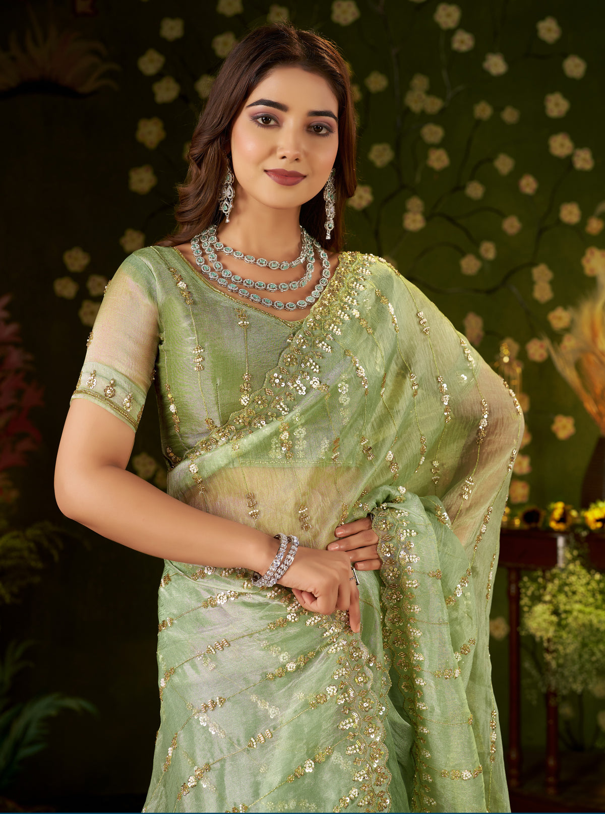 close-up of premium light-reflecting pistachio green tissue silk fabric and gold threads.
