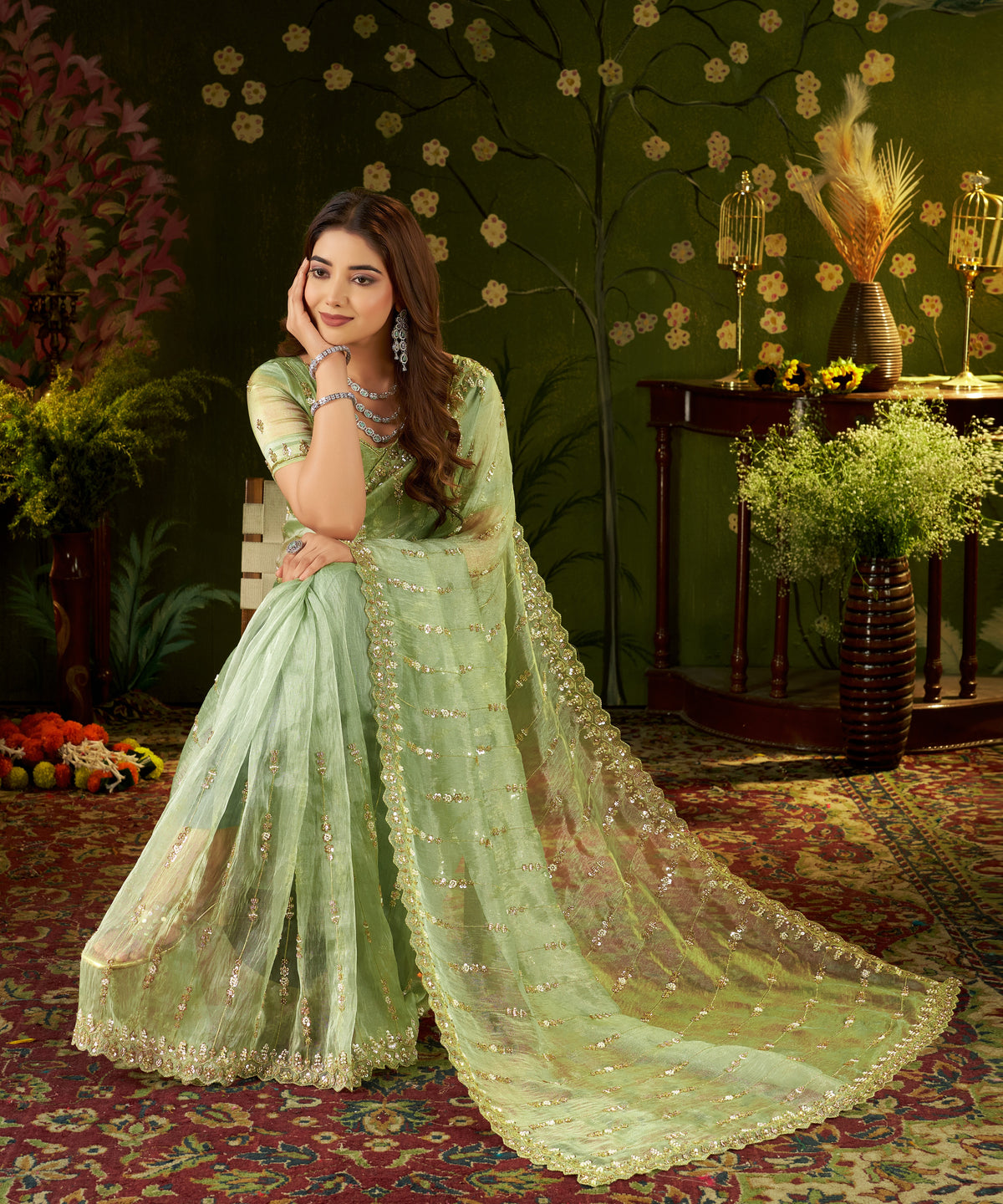 Seated shot showcasing the rich texture and rich handwork of pistachio green tissue saree.